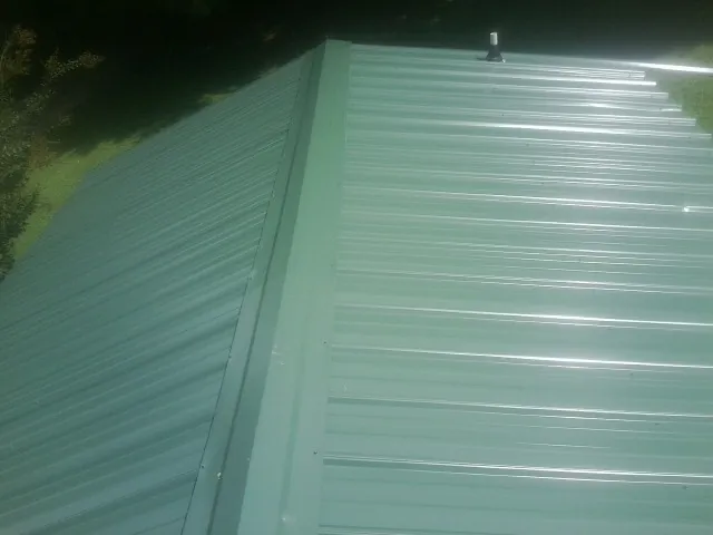 New green metal panels meeting at the ridge of a roof — Flat Roof Repair work by our crew in Eldorado