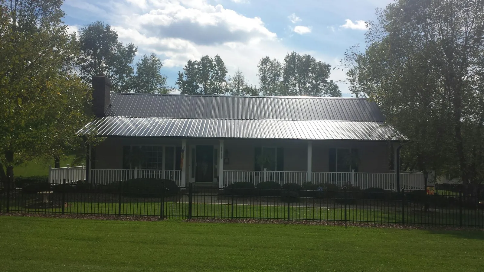 Gray metal roof on a brick ranch with a full width front porch — Gutter Guard Installation work by our crew in Eldorado