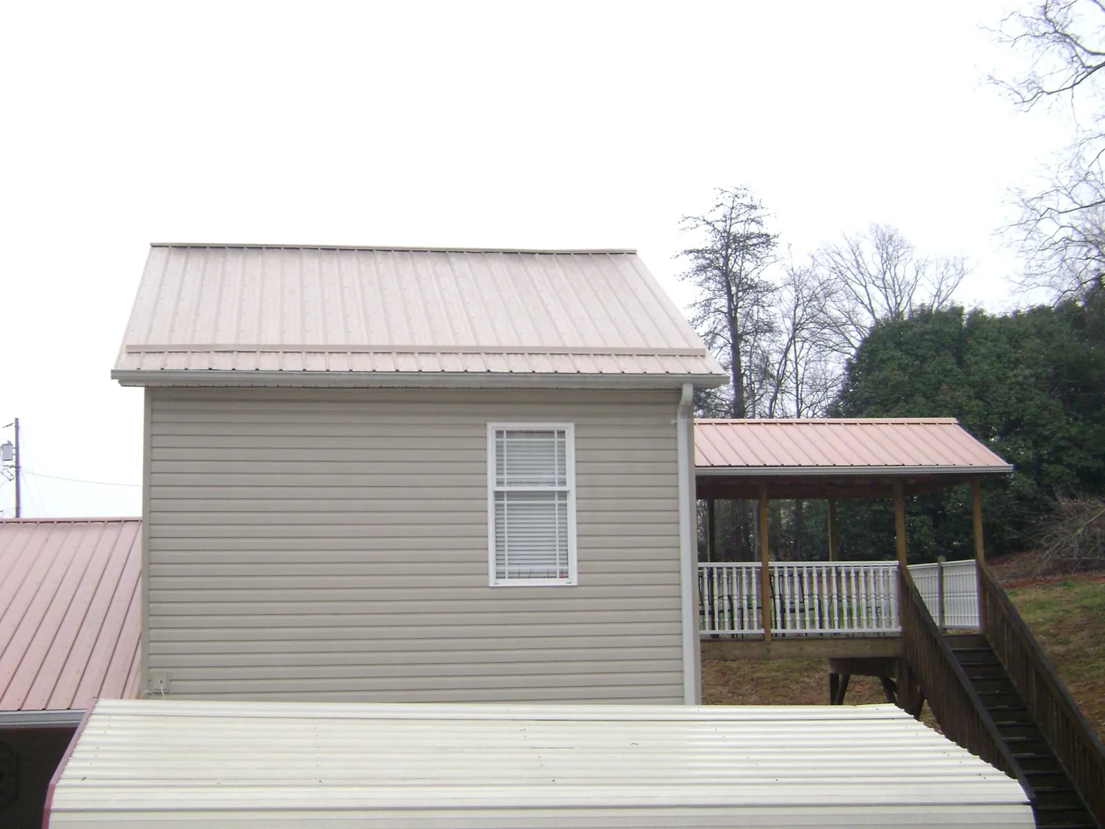 Tan metal roofs on a two story addition and attached porch, from a Roof Replacement job in Eldorado