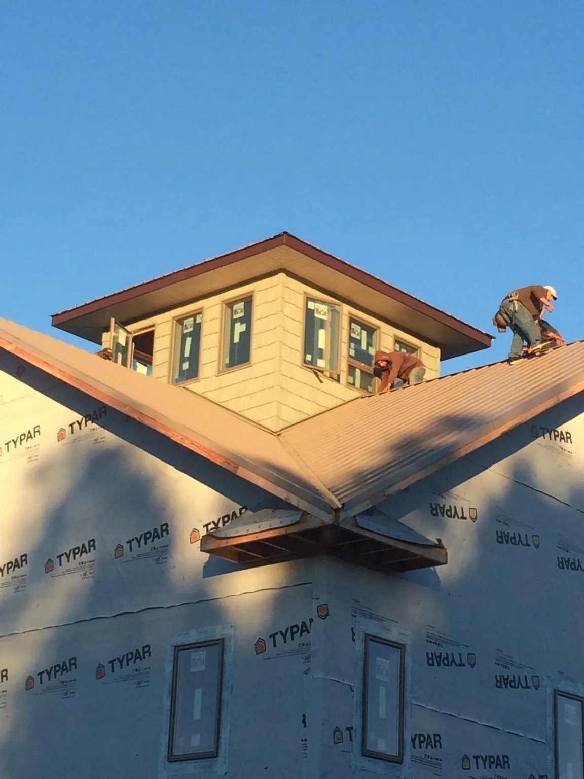 Roofers working around a rooftop cupola on a new metal roof at sunset — Roof Waterproofing in Eldorado by Roofing Brothers